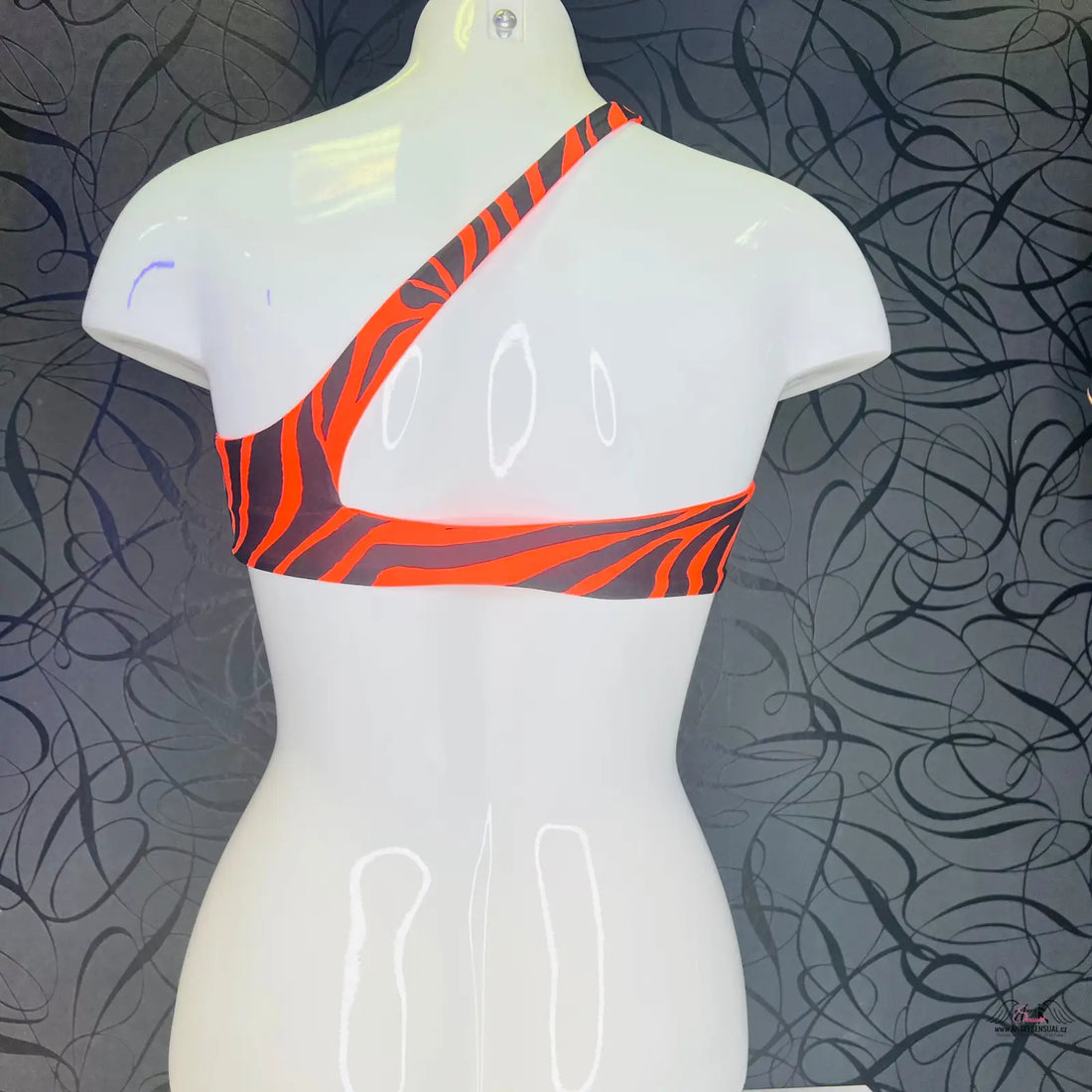 Bílá manekýnská trupa s asymetrickým sportovním topem s černo-červeným zebrovým vzorem, ideální jako horní díl plavek