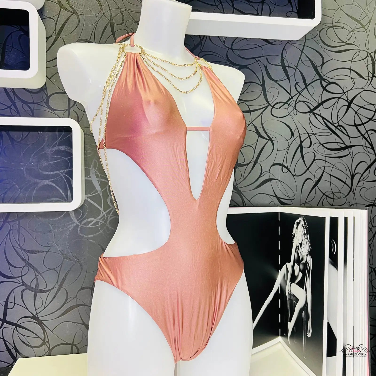 Peachové jednodílné plavky Kiona s průstřihem a zlatými doplňky na figuríně