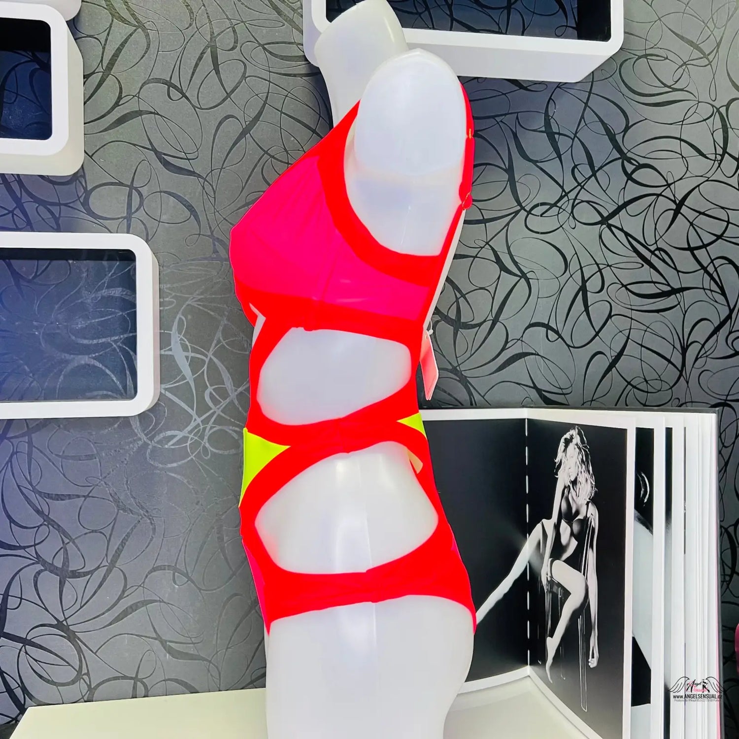 Fotografie plavky Mazzy s červeným abstraktním sochařským designem a žlutým akcentem