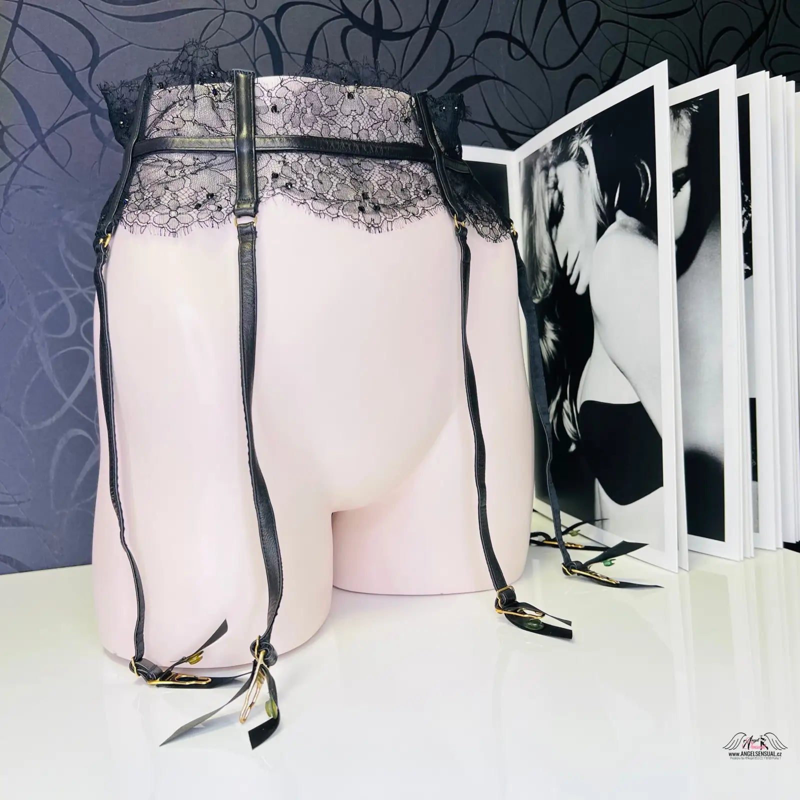 Lace-trimmed garter belt on mannequin with photo album, luxusní krajkový podvazkový pás adara s Černými kamínky