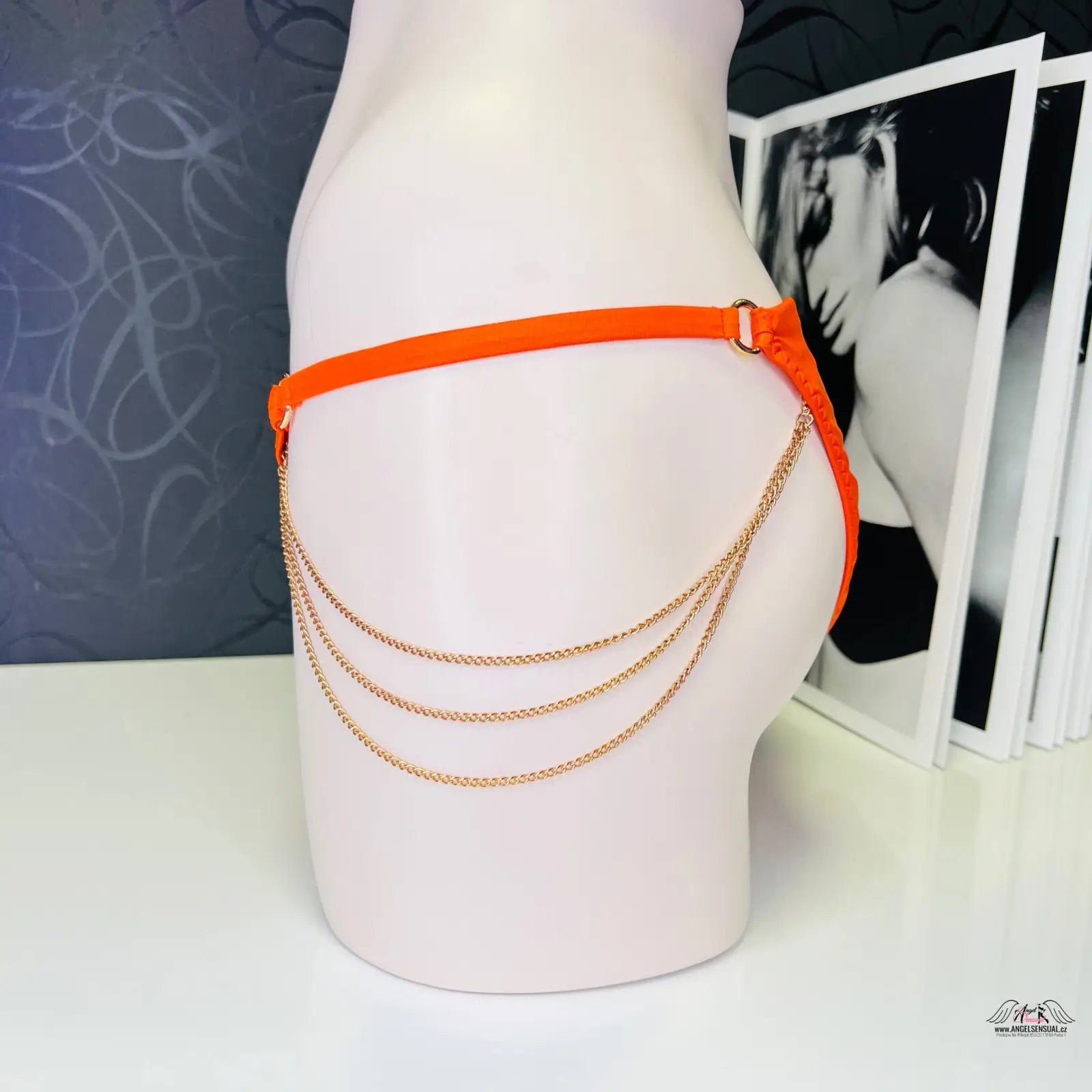 Orange belt with hanging gold chains on mannequin’s hip, plavek Tonya sytě oranžový spodní díl zlatými detaily