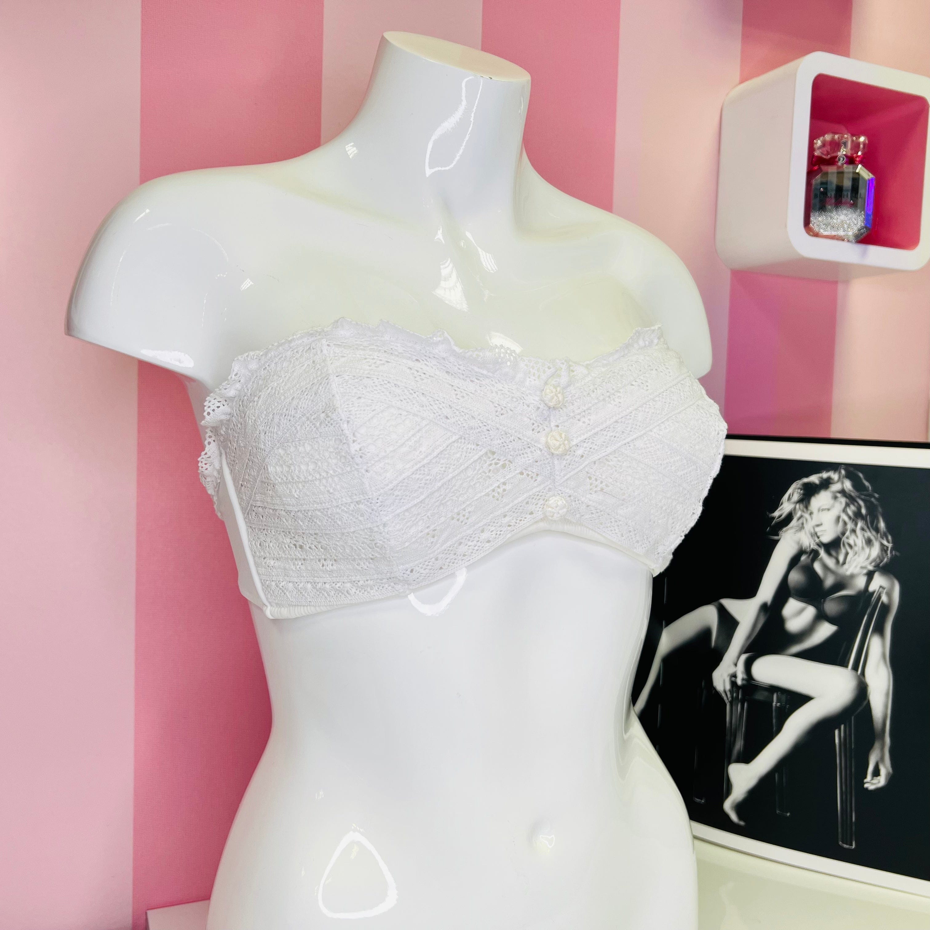 Bílá krajková korzetová podprsenka s ozdobnými knoflíčky na mannequinovi