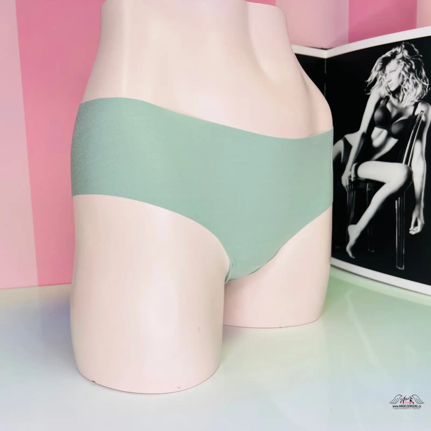 Žena v zelených bezešvých kalhotkách s růžovo-bílo pruhovaným pozadím