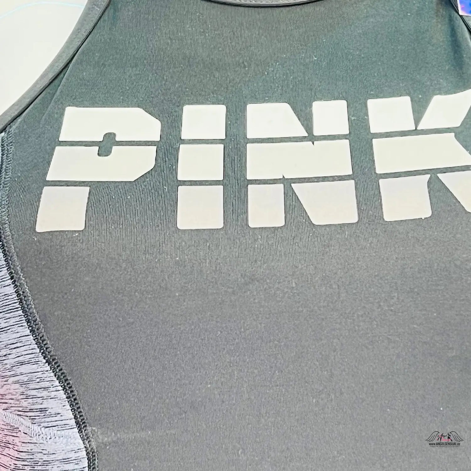 Šedé sportovní top s bílým nápisem, delší sportovní podprsenka trochu delšího střihu