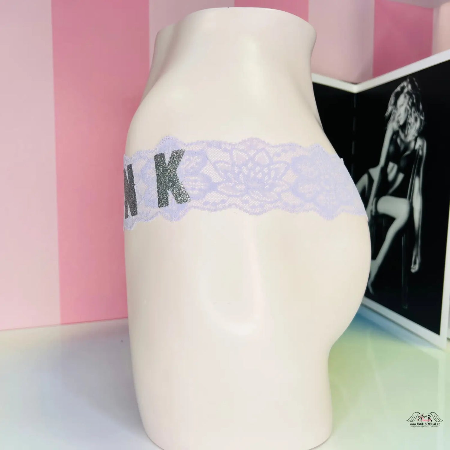 Žena na figuríně v krajkových kalhotkách s nápisem pink a stříbrným nápisem