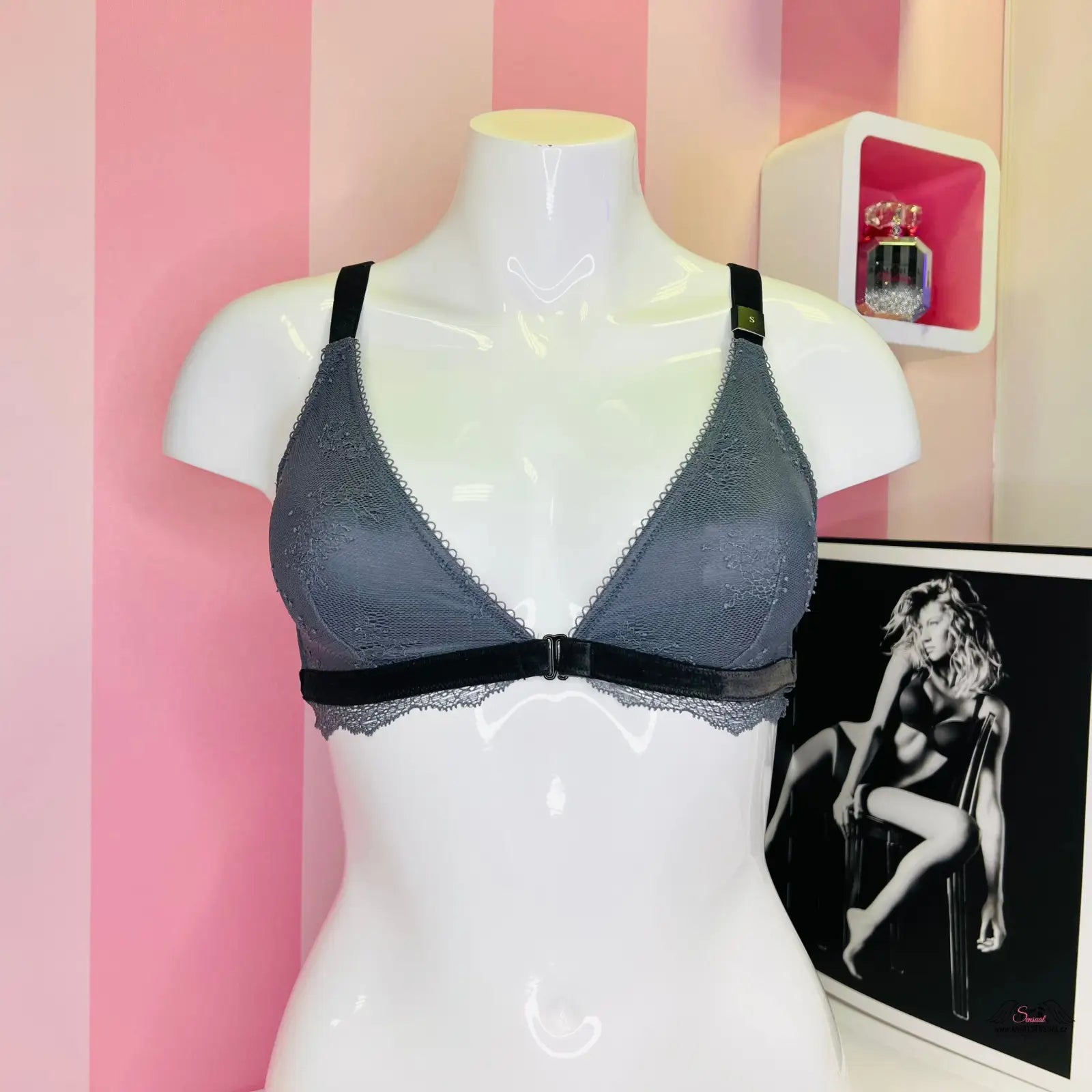 Arafed mannequin s krajkovým červeným bralette a nastavitelnými popruhy před růžovou pruhovanou stěnou