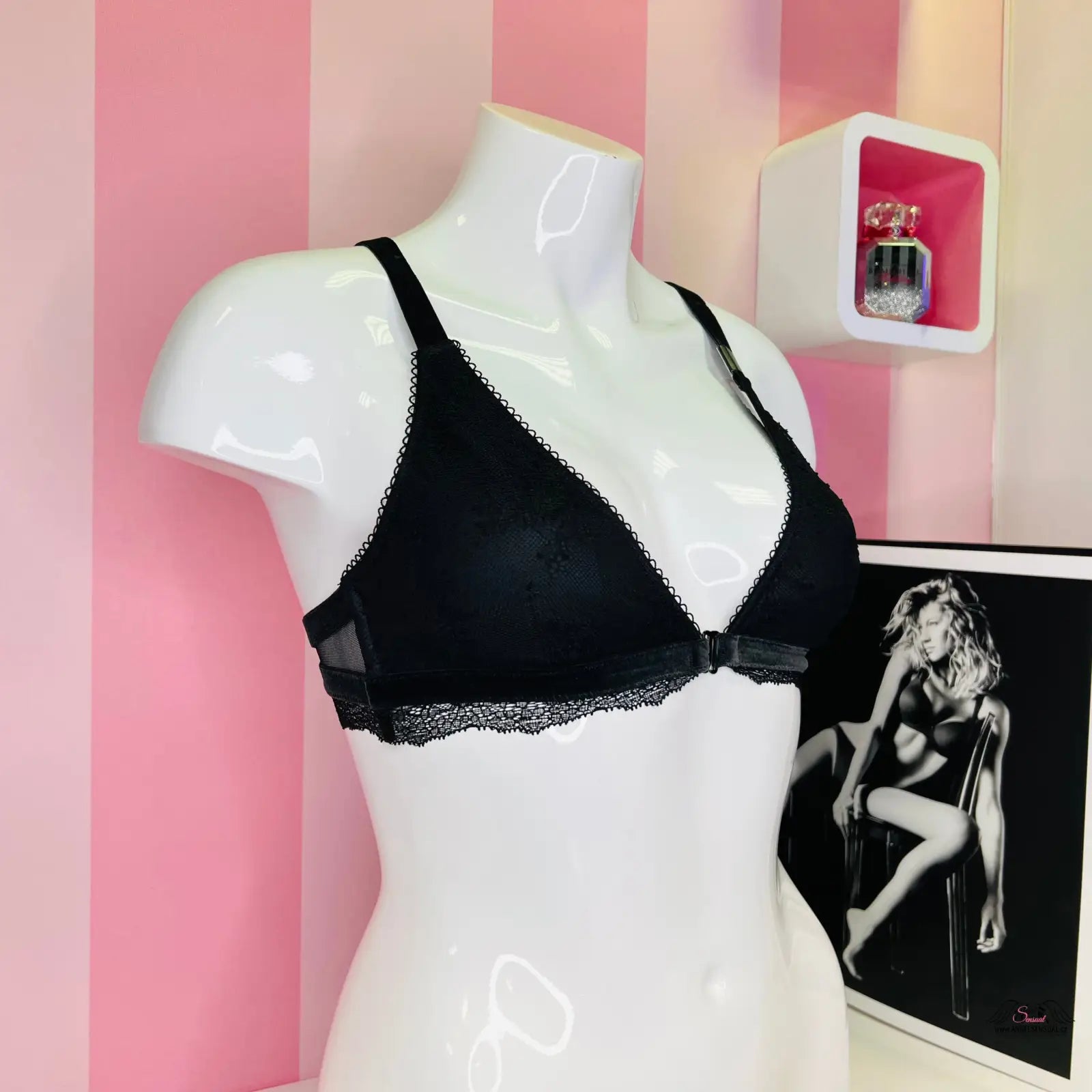 Manekýn s krajkovým červeným braletem Victoria’s Secret s nastavitelnými popruhy před pruhovanou stěnou