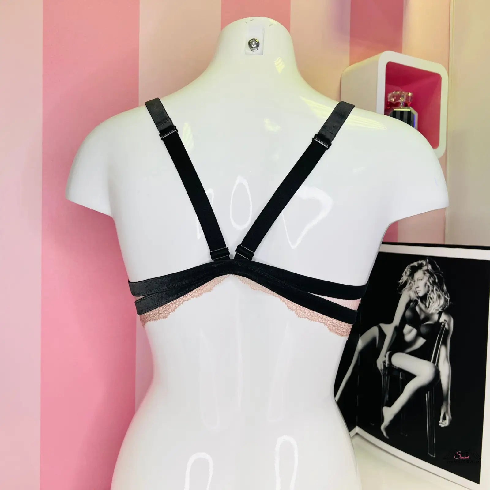 Arafed mannequin s krajkovým červeným bralette Agent Provocateur s nastavitelnými popruhy před růžovou pruhovanou stěnou