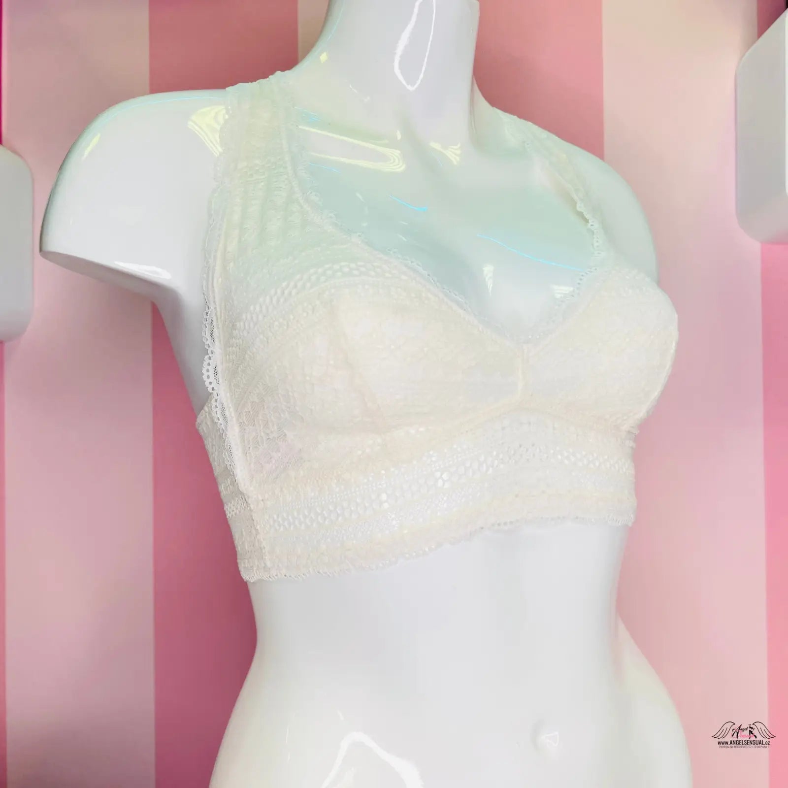 Manekýn s bílou lákavou krajkovou braletkou Victoria’s Secret na růžové pruhované stěně