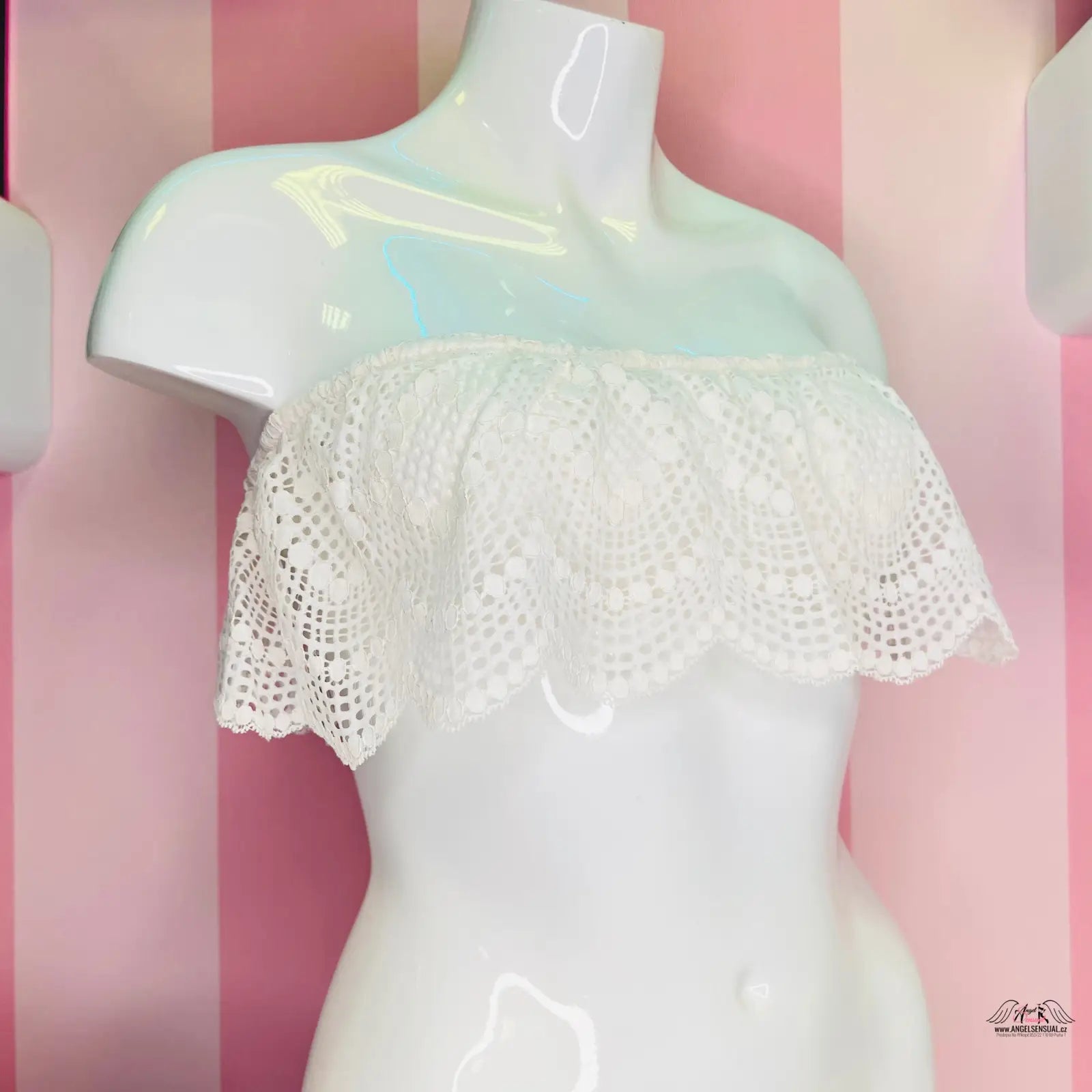 Manekýn s bílou braletkou Victoria’s Secret s růžovo-bílým pruhovaným pozadím