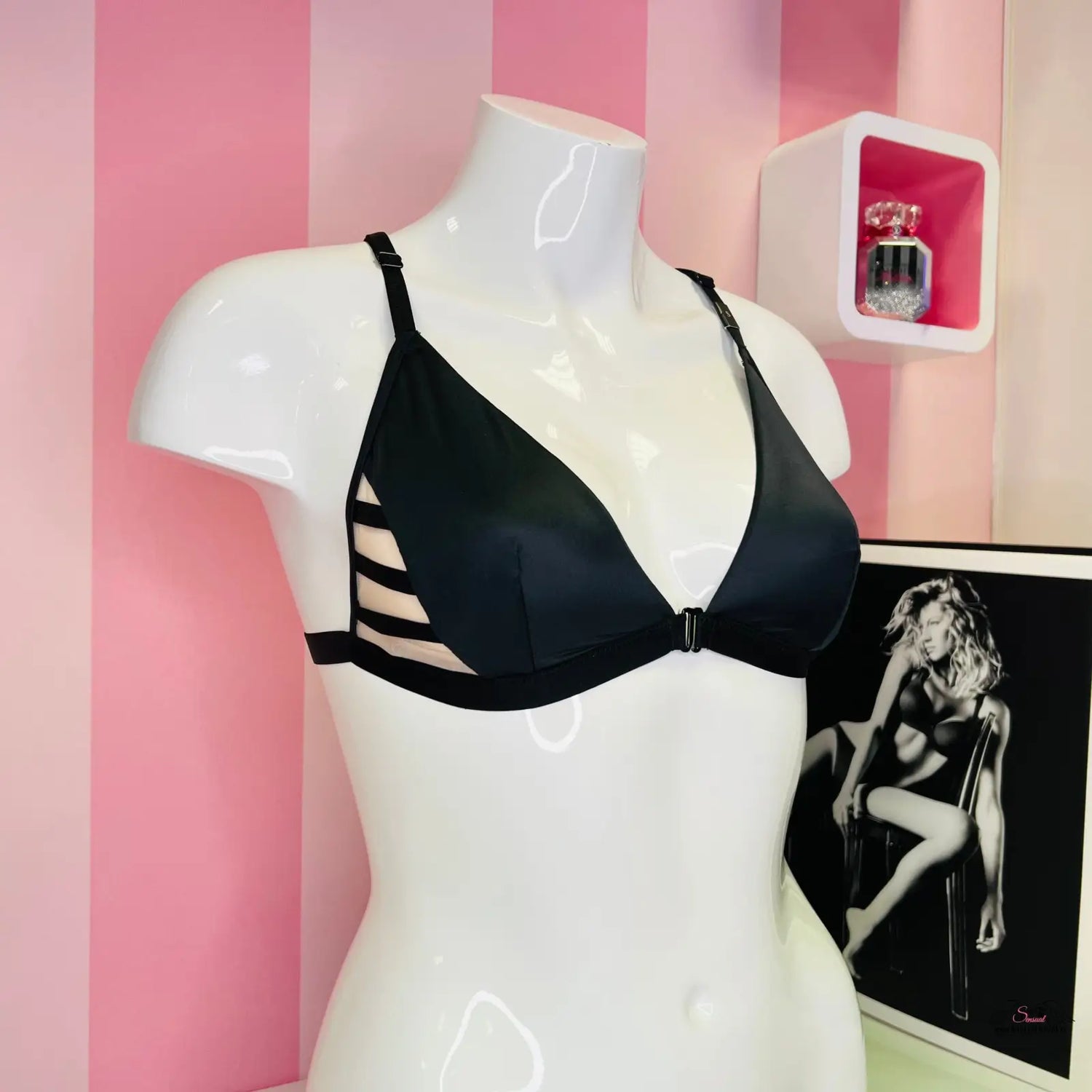 Arafed mannequin v victoria’s secret lesklá braletka s mesh panely na růžové pruhované zdi