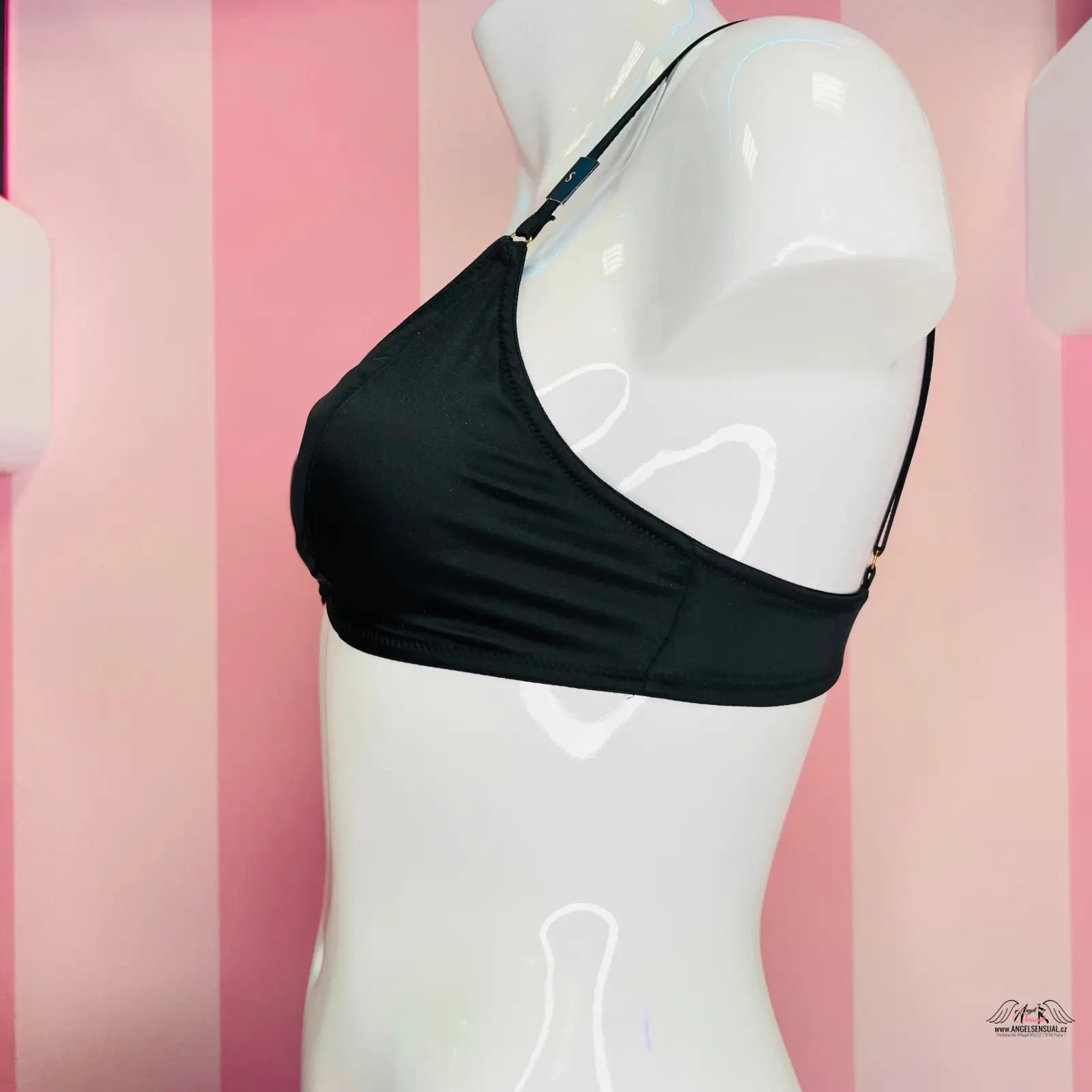 Manekýn v černé barvě braletka s přední aplikací na růžové pruhované stěně