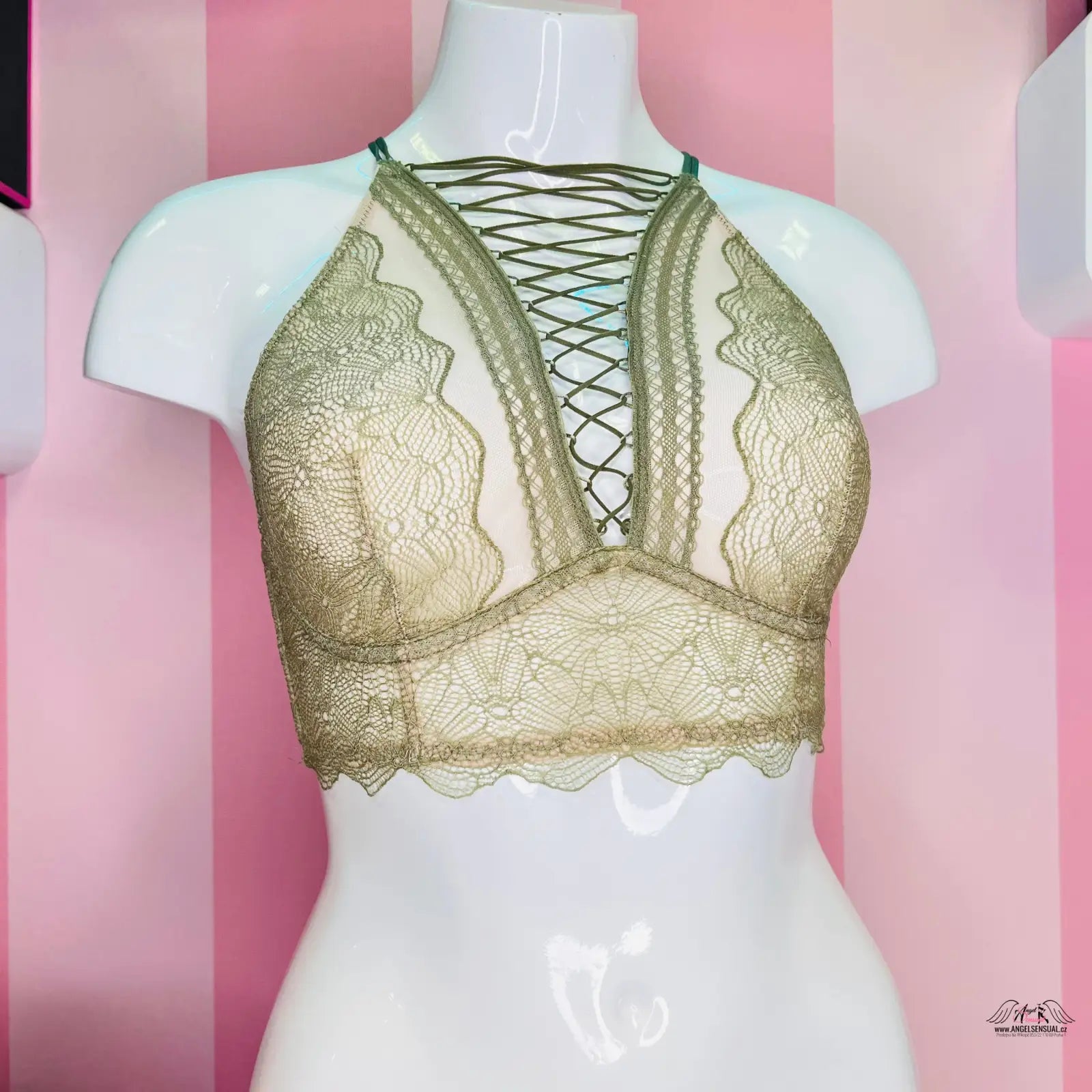 Detailní pohled na zlatou podprsenku Victoria’s Secret s překříženými ramínky a výšivkou