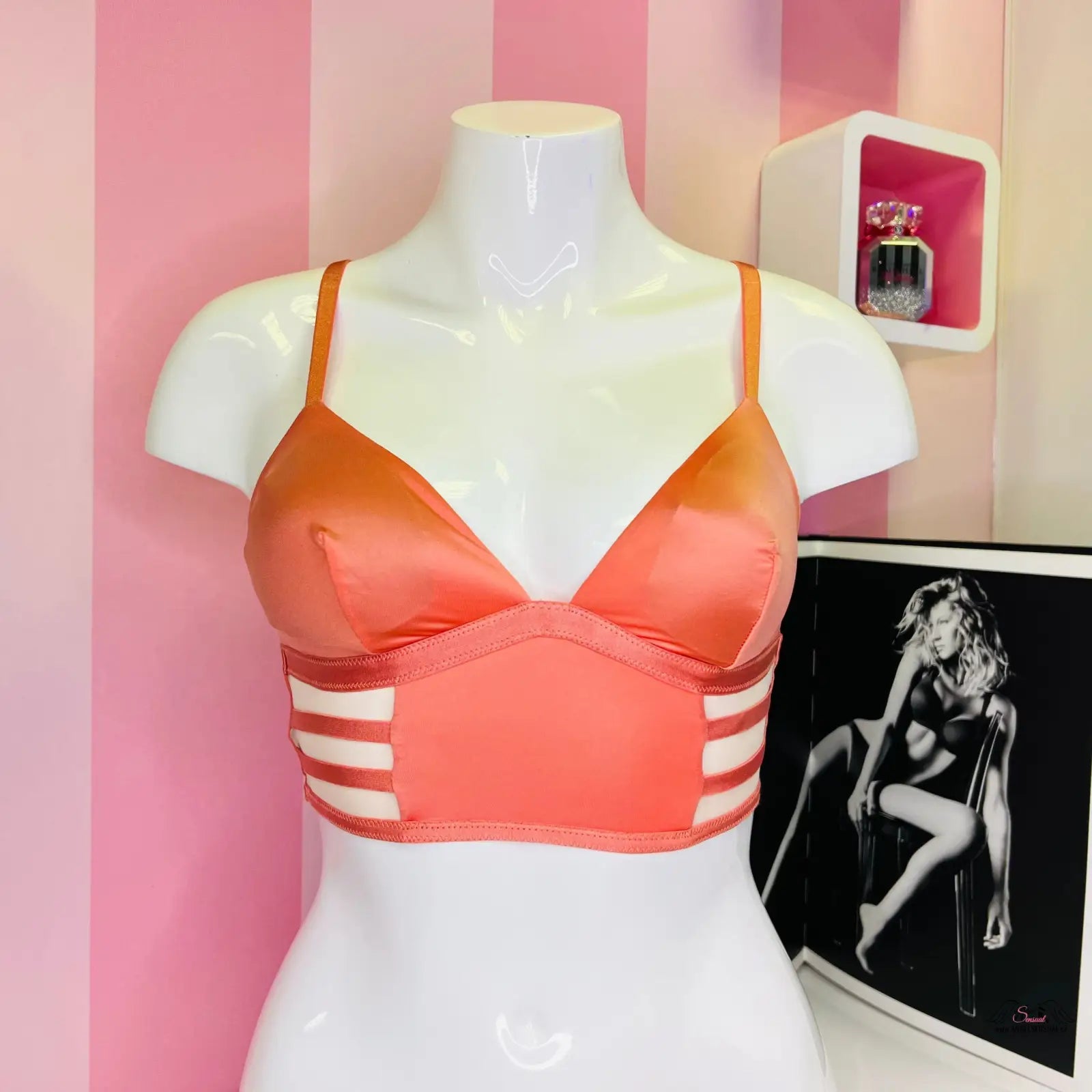 Oranžovo-růžová sportovní nebo plavková podprsenka s pruhovanými bočními panely na bílém modelu, ideální jako měkká strečová bralet