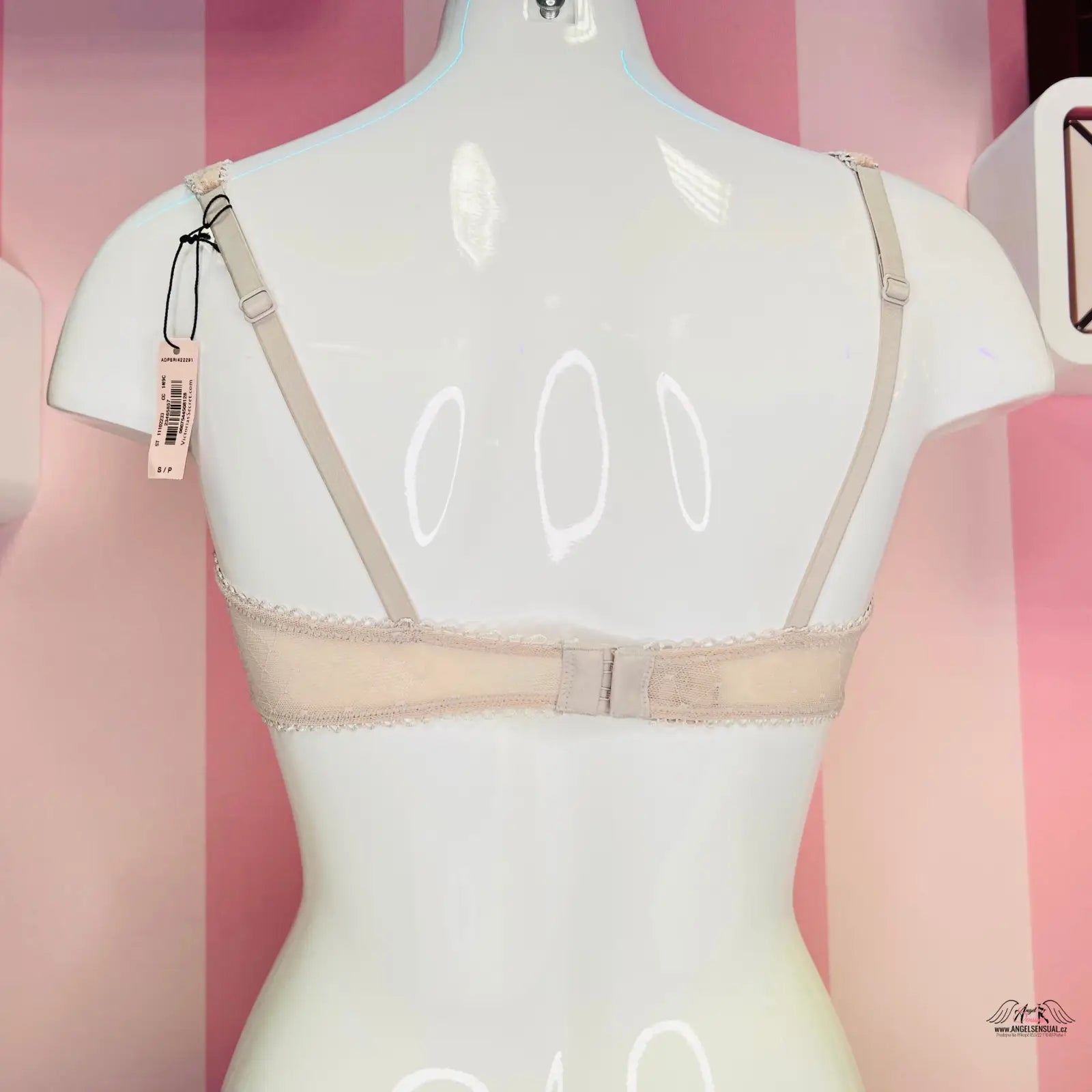 Bílá mannequin s béžovou síťovanou braletkou s krajkovými detaily a bílou krajkou