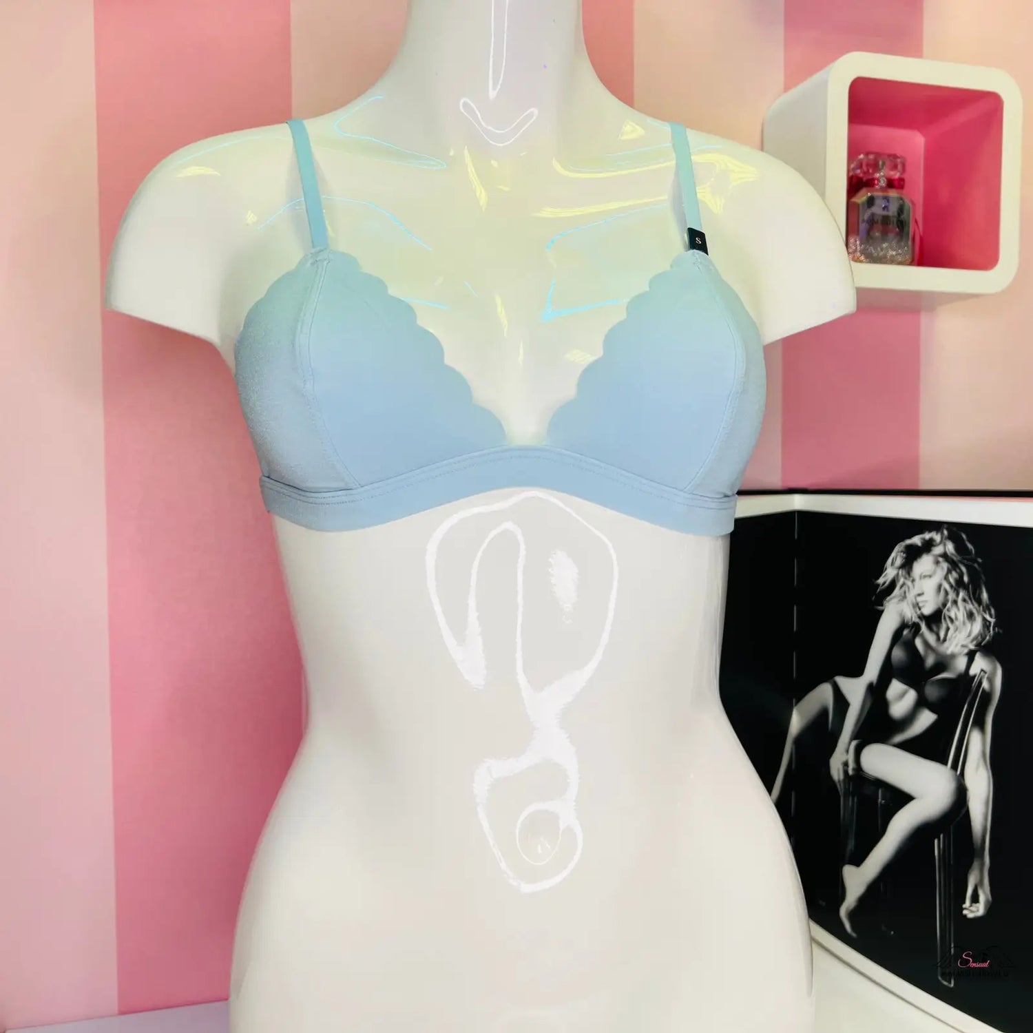 Manekýn s modrým braletem Victoria’s Secret s posuvnými popruhy na růžové stěně