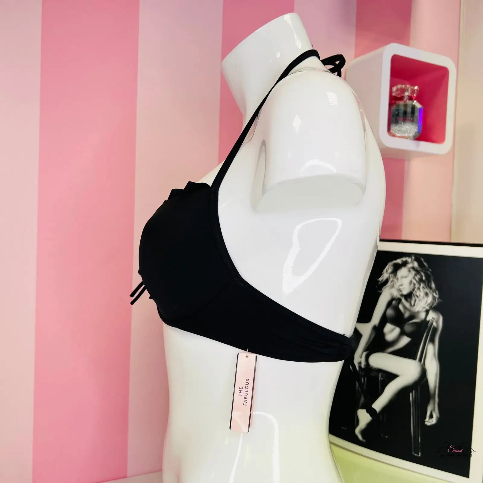 Manne s černým plavkovým topem Victoria’s Secret před růžovo-bíle pruhovanou stěnou
