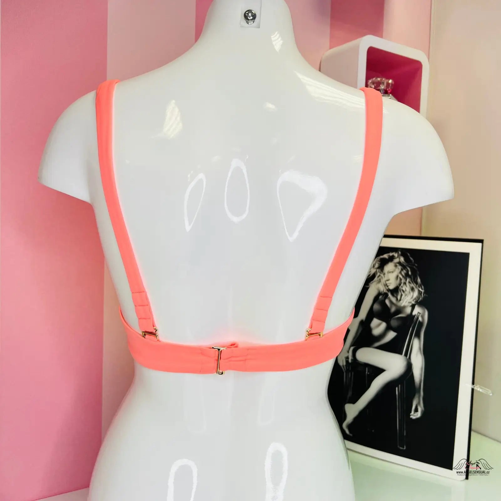 White mannequin torso s korálovým horním dílem plavek s jemnou zlatou ozdobou