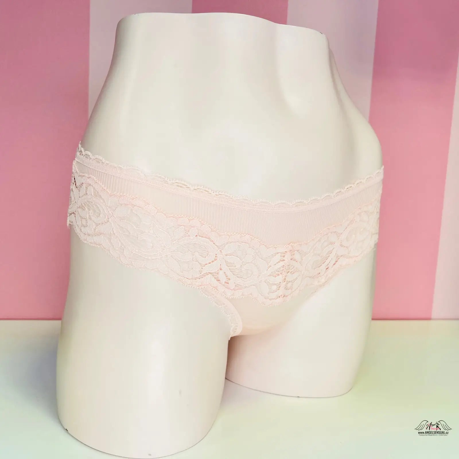 Bílá mannequin s jemnými kalhotkami Victoria’s Secret s ozdobnou krajkou před růžovo-bílou stěnou