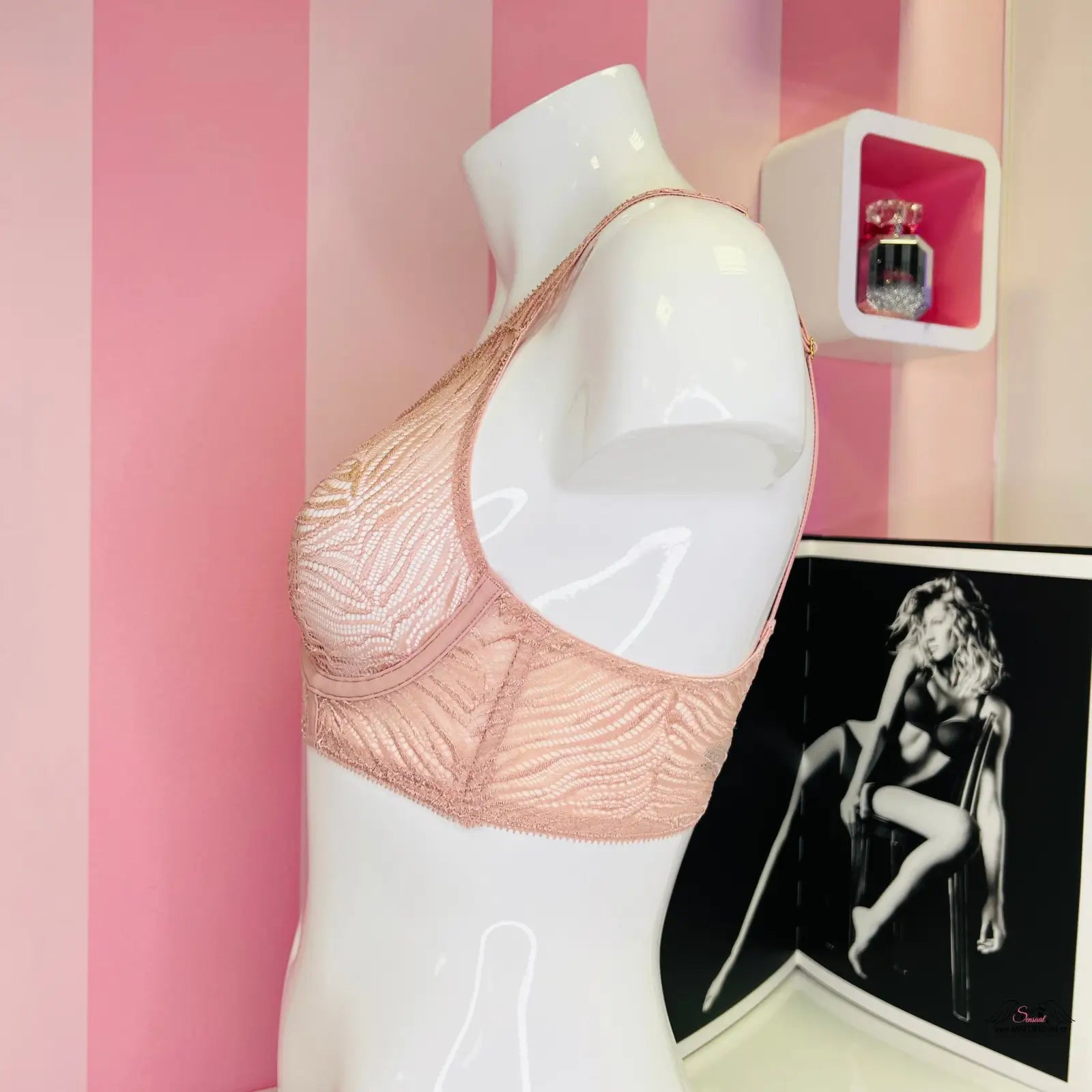 Manekýn v Victoria’s Secret Podprsenka Průsvitná s Vystužením před růžovo-bílou pruhovanou stěnou, krásně podepřené poprsí s