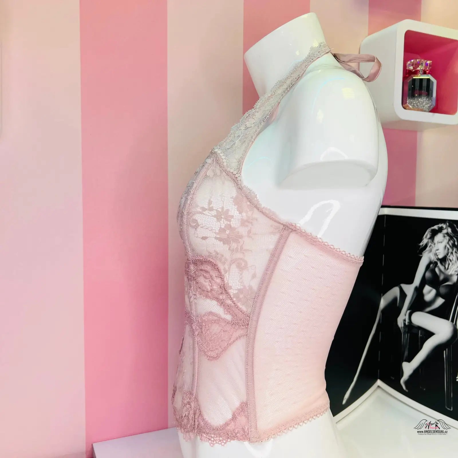 Manekýn s růžovo-bíle pruhovanou stěnou v pozadí, ukazuje svůdný růžový korzet Victoria’s Secret