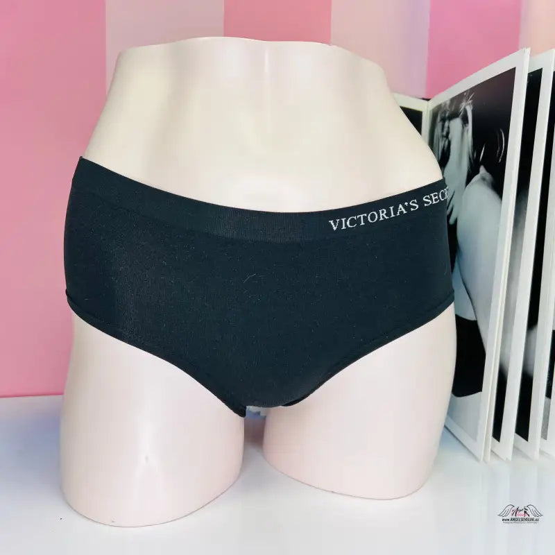 Arafed mužský torzo v černých kalhotkách Victoria’s Secret před růžovou pruhovanou stěnou