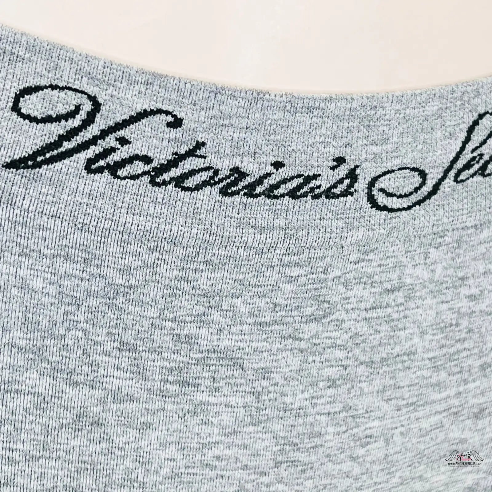 Žena v stylových šedých tangách Victoria’s Secret s černým nápisem láska