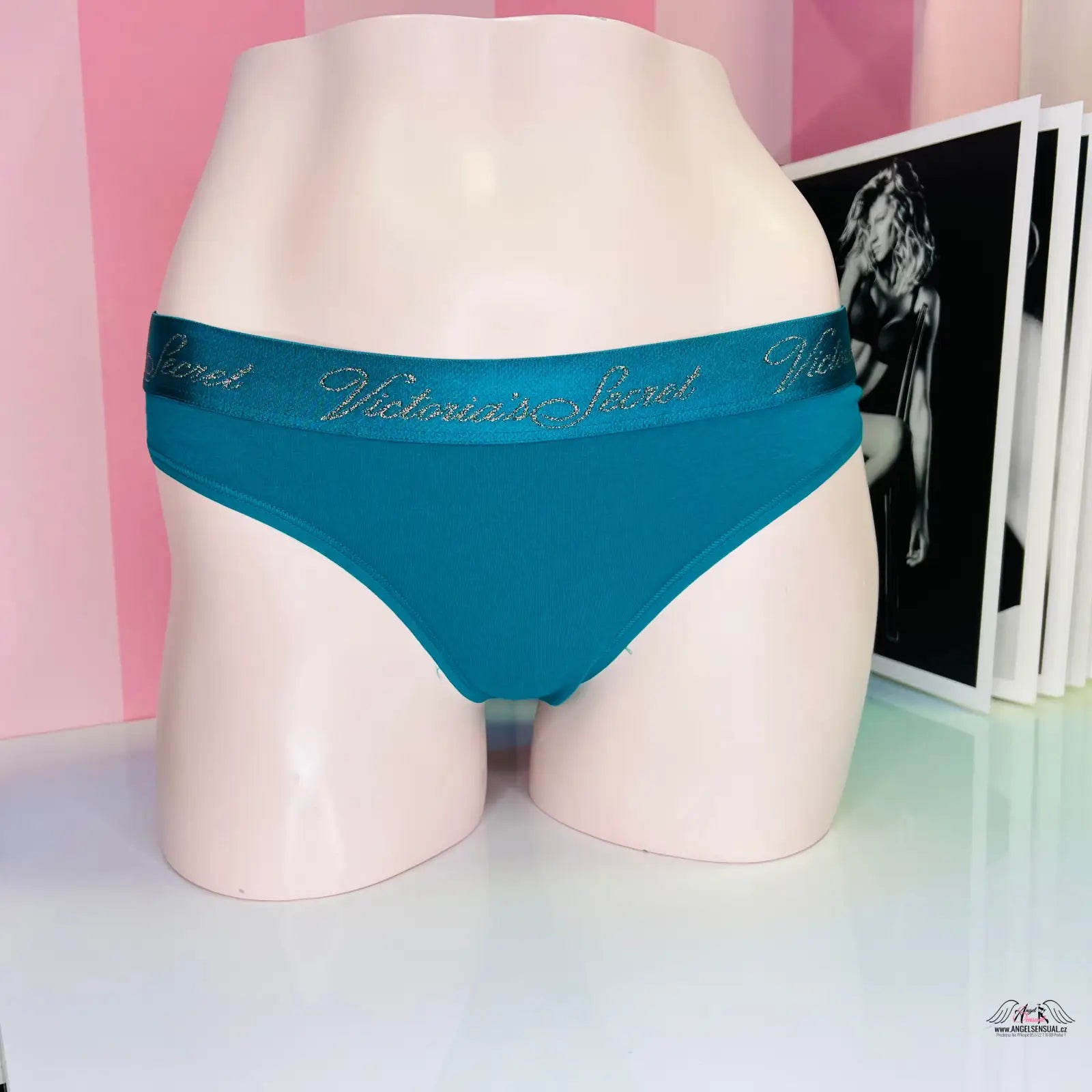 Victoria’s Secret petrolejová tanga s zlatým nápisem a černobílou fotografií ženy mannequin