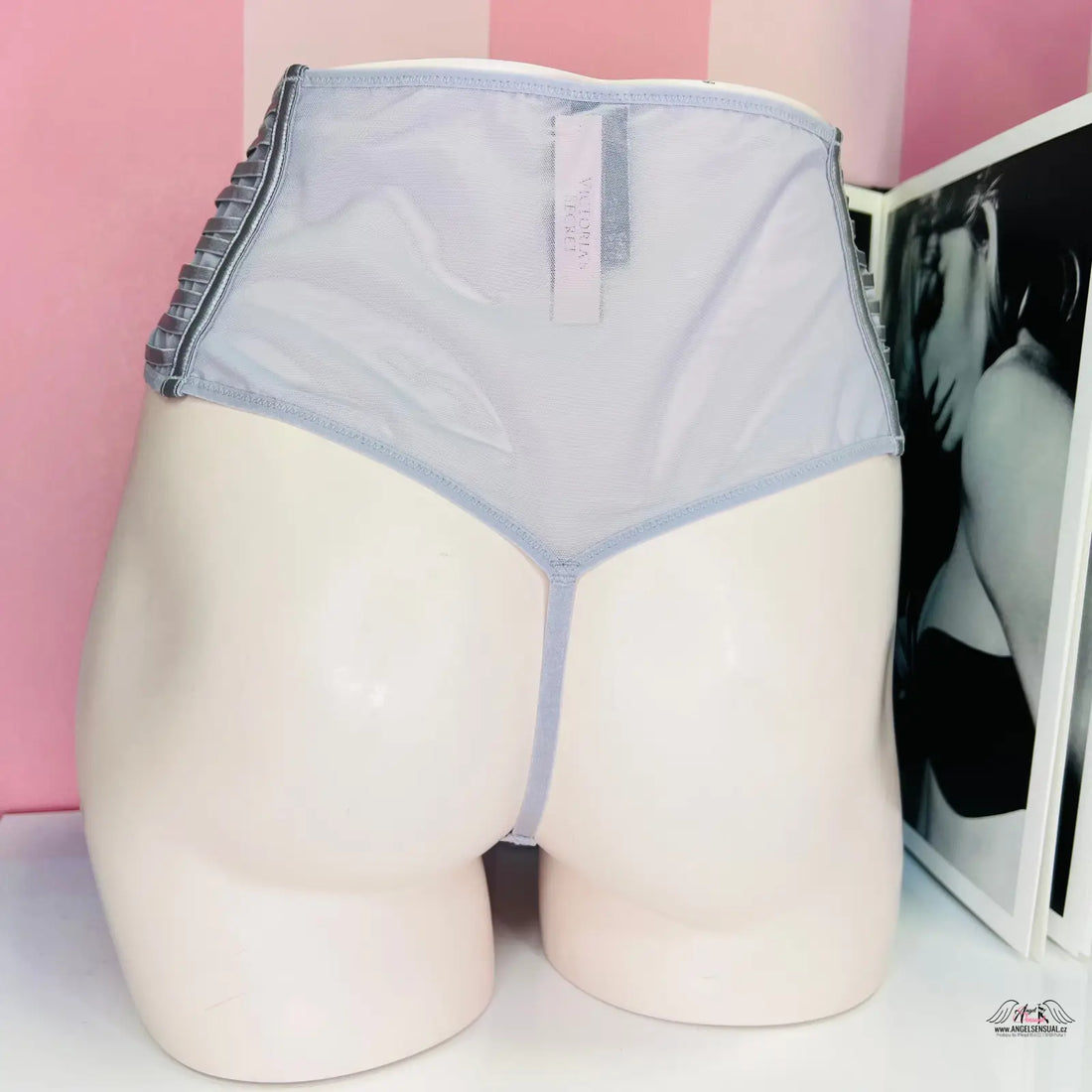 Bílá figurína v modrých tanga s vysokým pasem na růžové stěně, ideální spodní prádlo