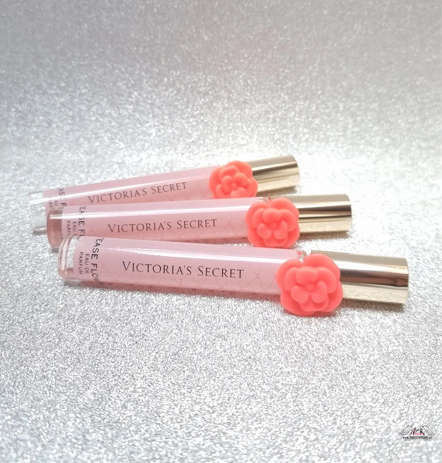 Tři růžové Victoria’s Secret Tease Flower roll-on parfémy s korálovými květinovými víčky