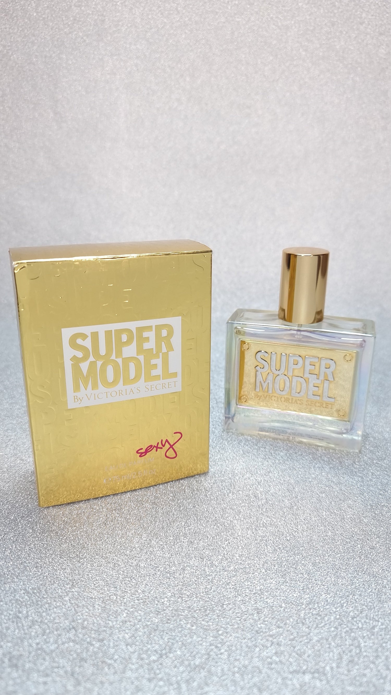 Goldová parfémová lahev a krabice od Victoria’s Secret Super Model EDP