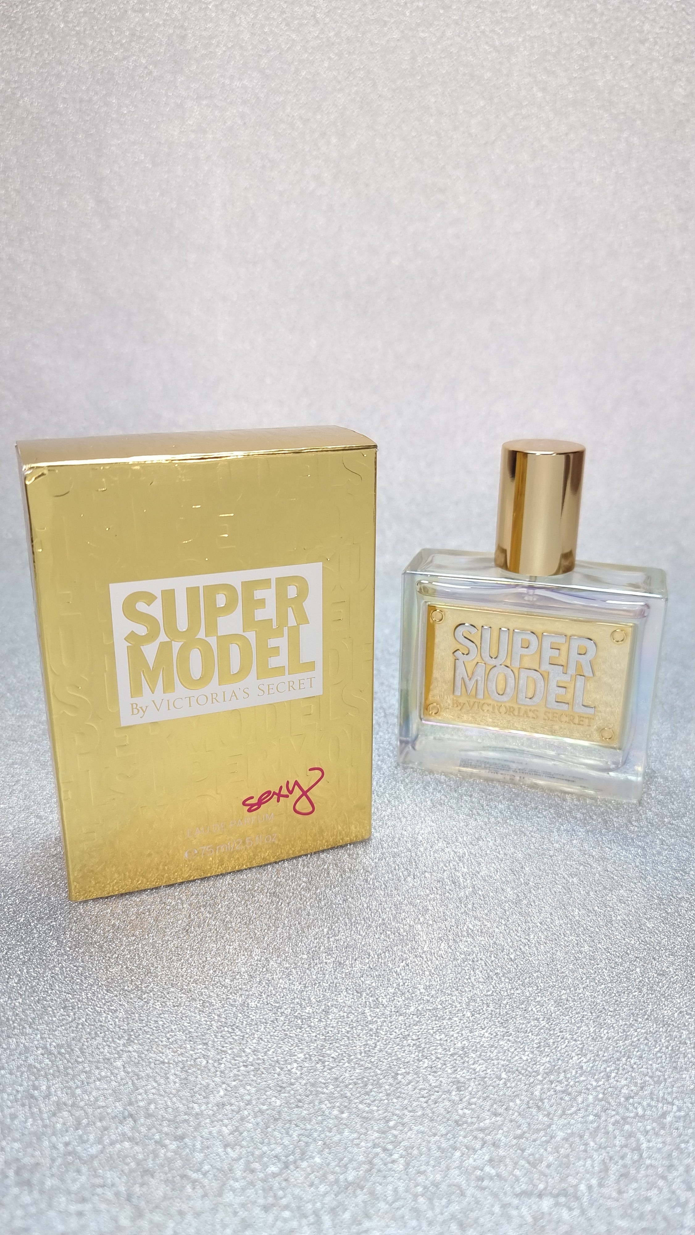 Goldová parfémová lahev a krabice od Victoria’s Secret Super Model EDP