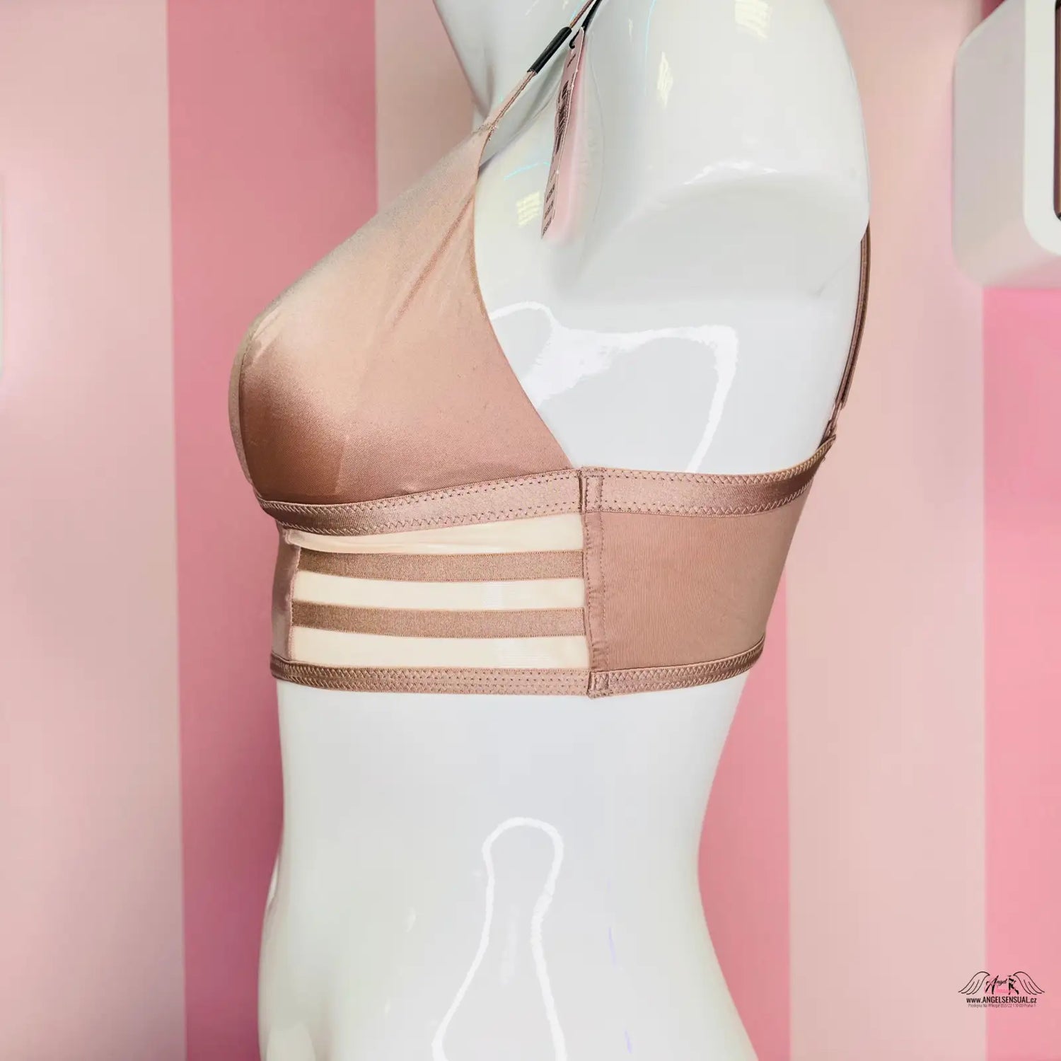 Nude podprsenka s řemínkovými detaily na pozadí růžové barvy