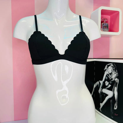 Mannequin with black bralette top against pink and white striped wall