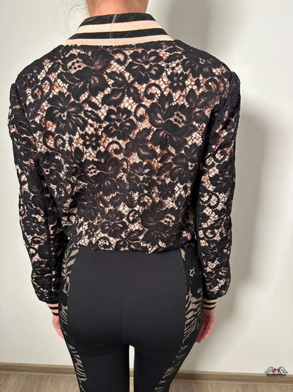 Záda ženy v černém a zlatém květinovém topu s elegantní bundou Codey Bomber