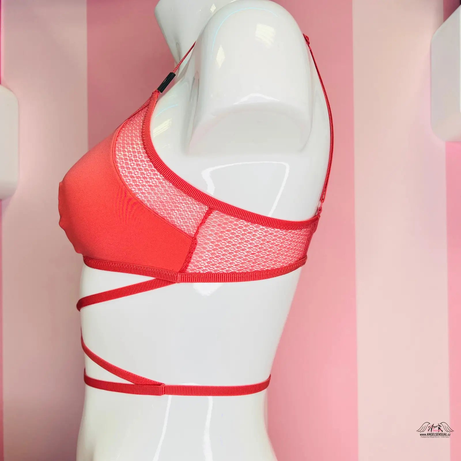Manekýn s červenou podprsenkou před růžově pruhovanou zdí Victoria’s Secret