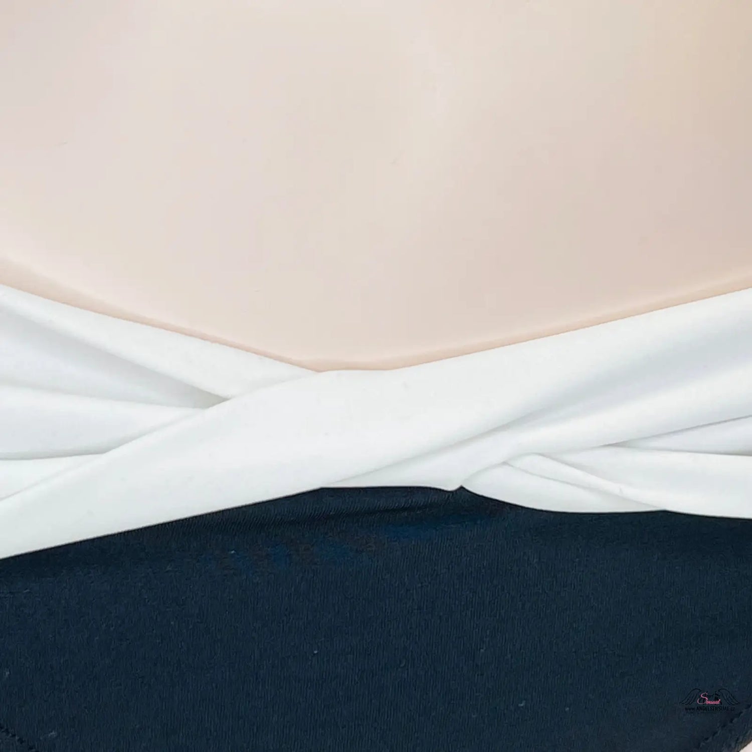 Bílá tkanina stočená a položena na tmavém povrchu pro Elegantní Křížené Plavky