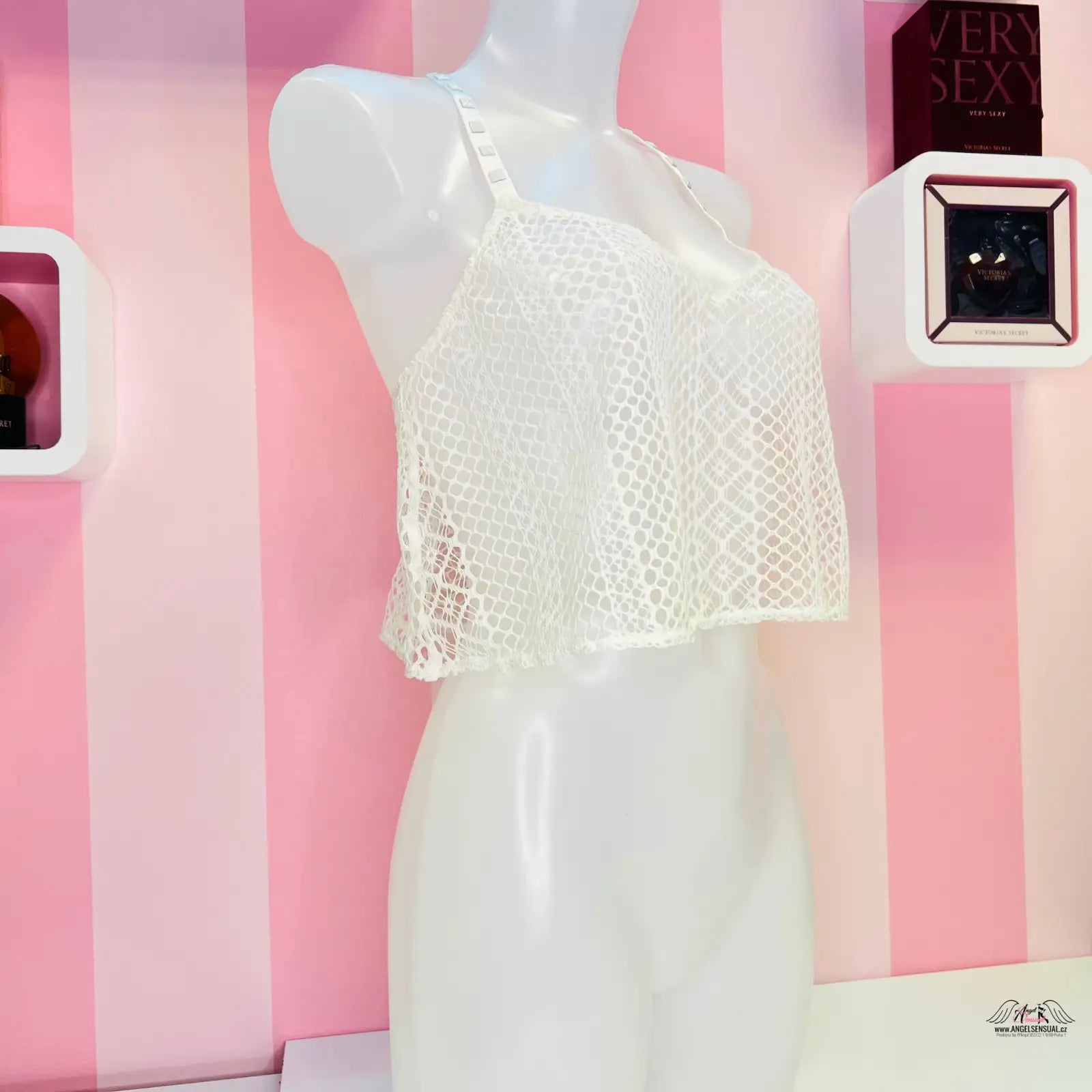 Bílý krajkový crop top vystavený na manekýně pro elegantní vzhled