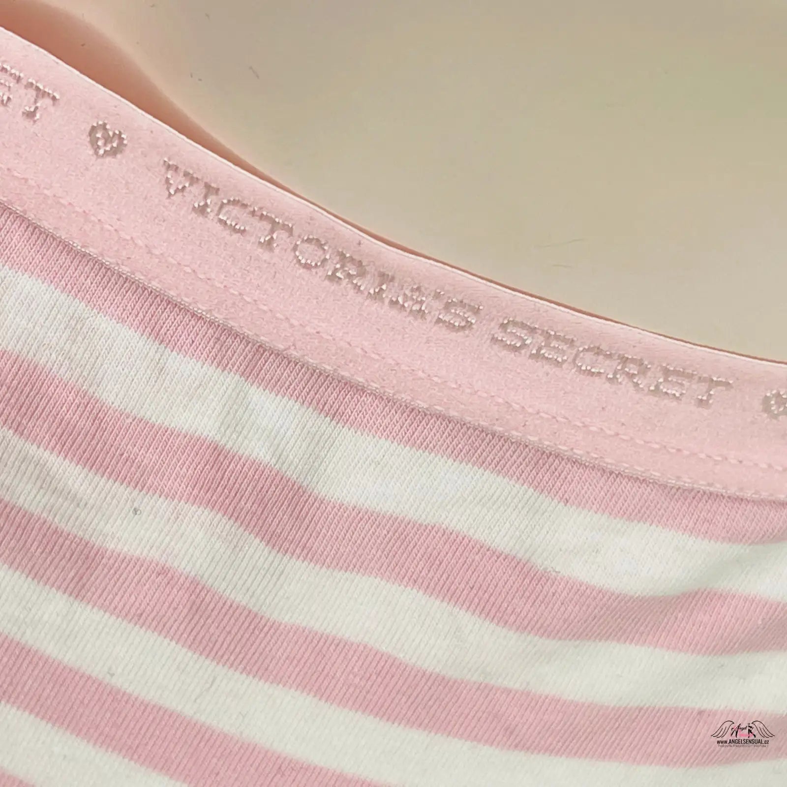 Žena v růžovo-bílém pruhovaném tričku, prezentující elegantní kalhotky