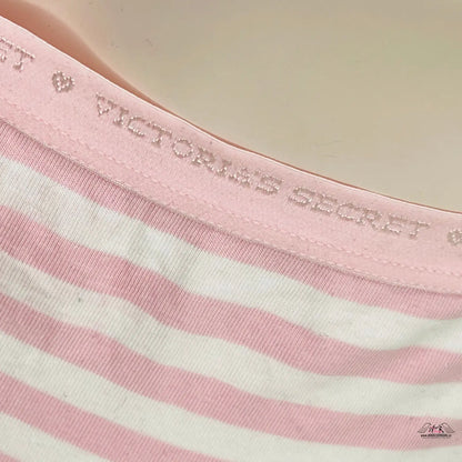 Žena v růžovo-bílém pruhovaném tričku, prezentující elegantní kalhotky