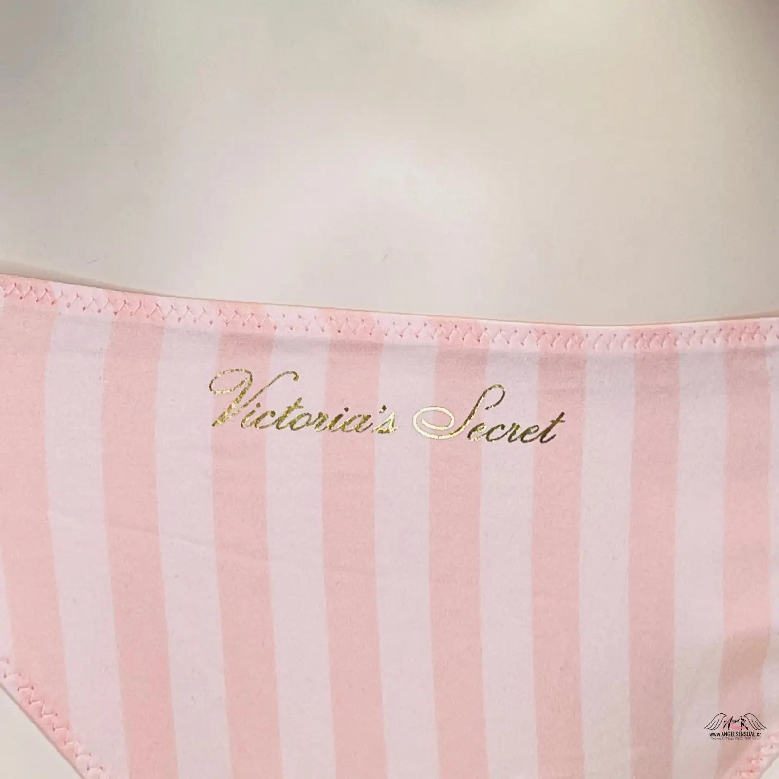 Růžovo-bílá pruhovaná látka se zlatým nápisem Victoria’s Secret