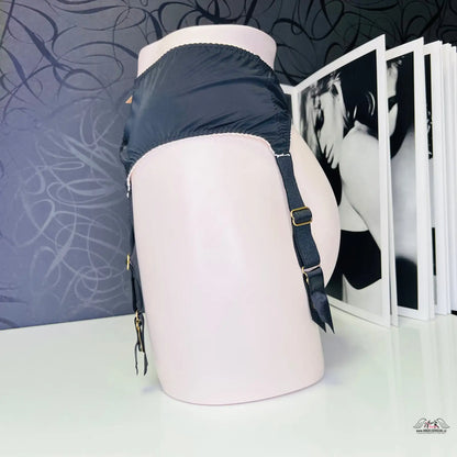 Růžový batoh na bílem stole vedle produktu Joseline Suspender v černé barvě