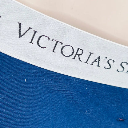 Logo Victoria’s Secret na bílém textilu s modrým pozadím produktu Komfortní Bavlněné Kalhotky pro Celodenní Pohodlí
