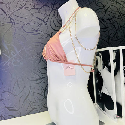 Růžový bikini top na bílém figuríně s luxusními zlatými ozdobami