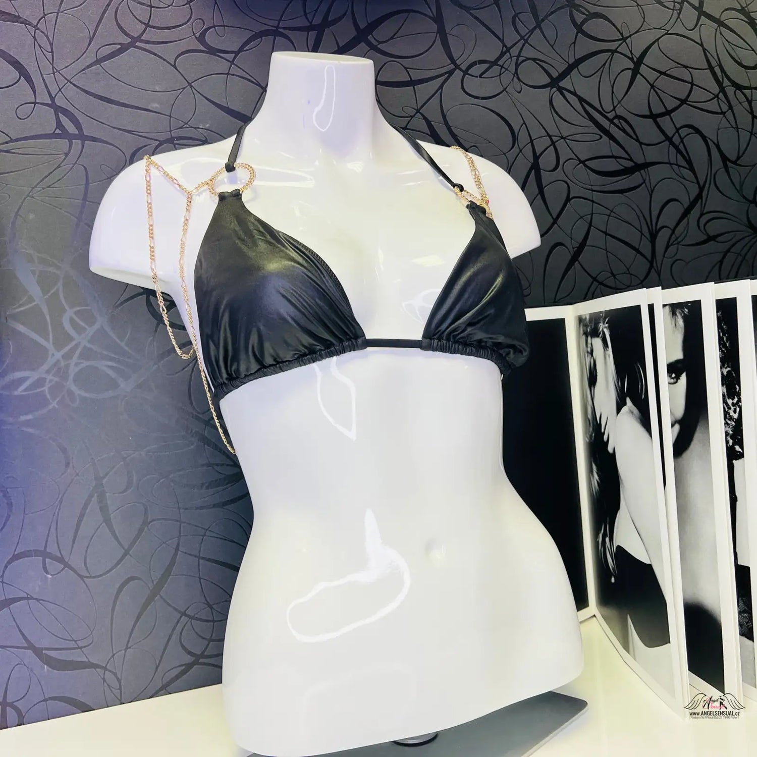 Bílý mannequin s černým trojúhelníkovým bikinovým topem se zlatými řetězy