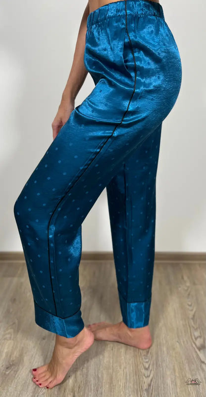 Žena v modrých kalhotách a bílém topu na dřevěné podlaze s luxusními pyžamovými kal