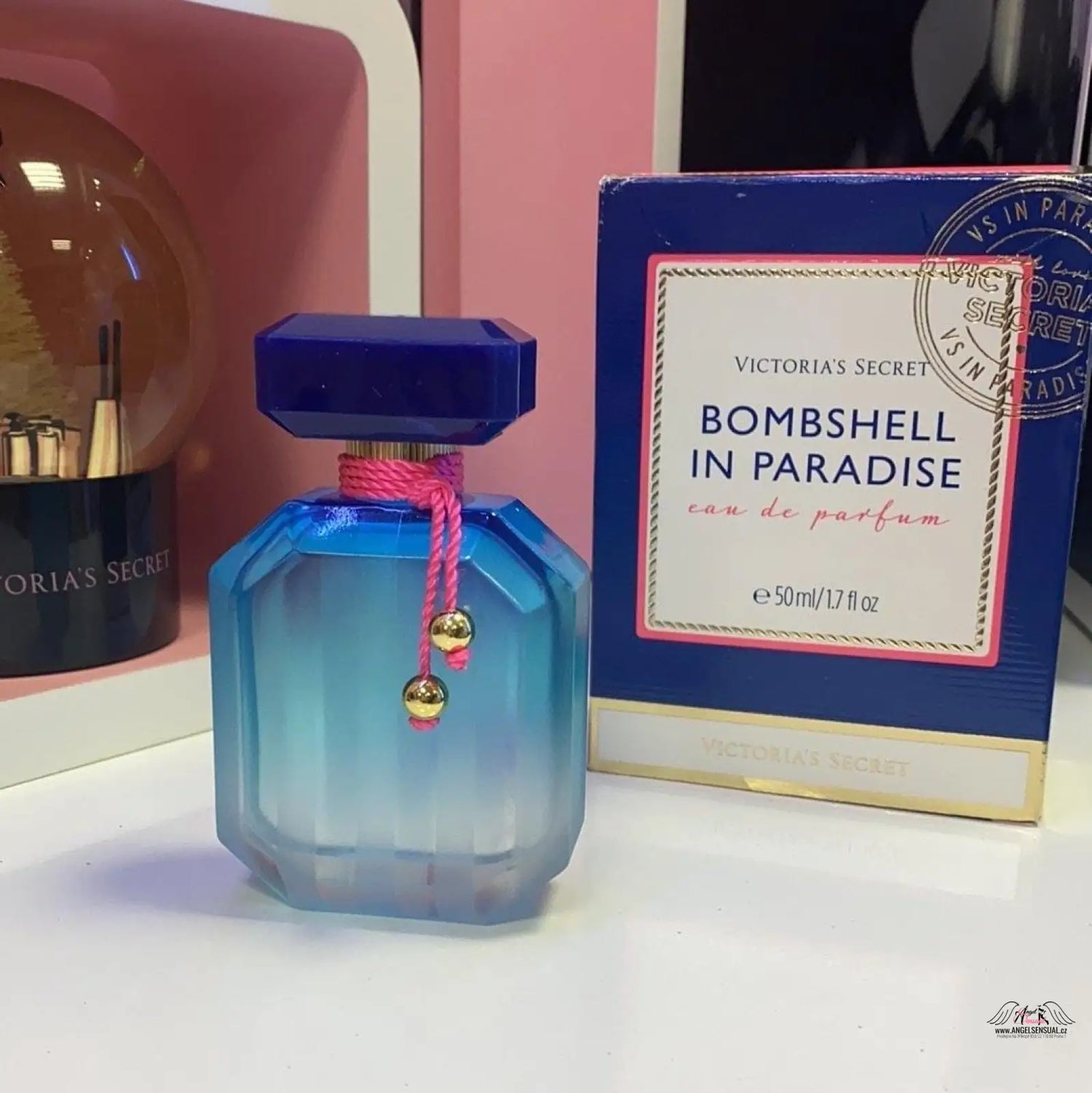 Flaška vůně Bombshell in Paradise od Victoria’s Secret na elegantním pozadí