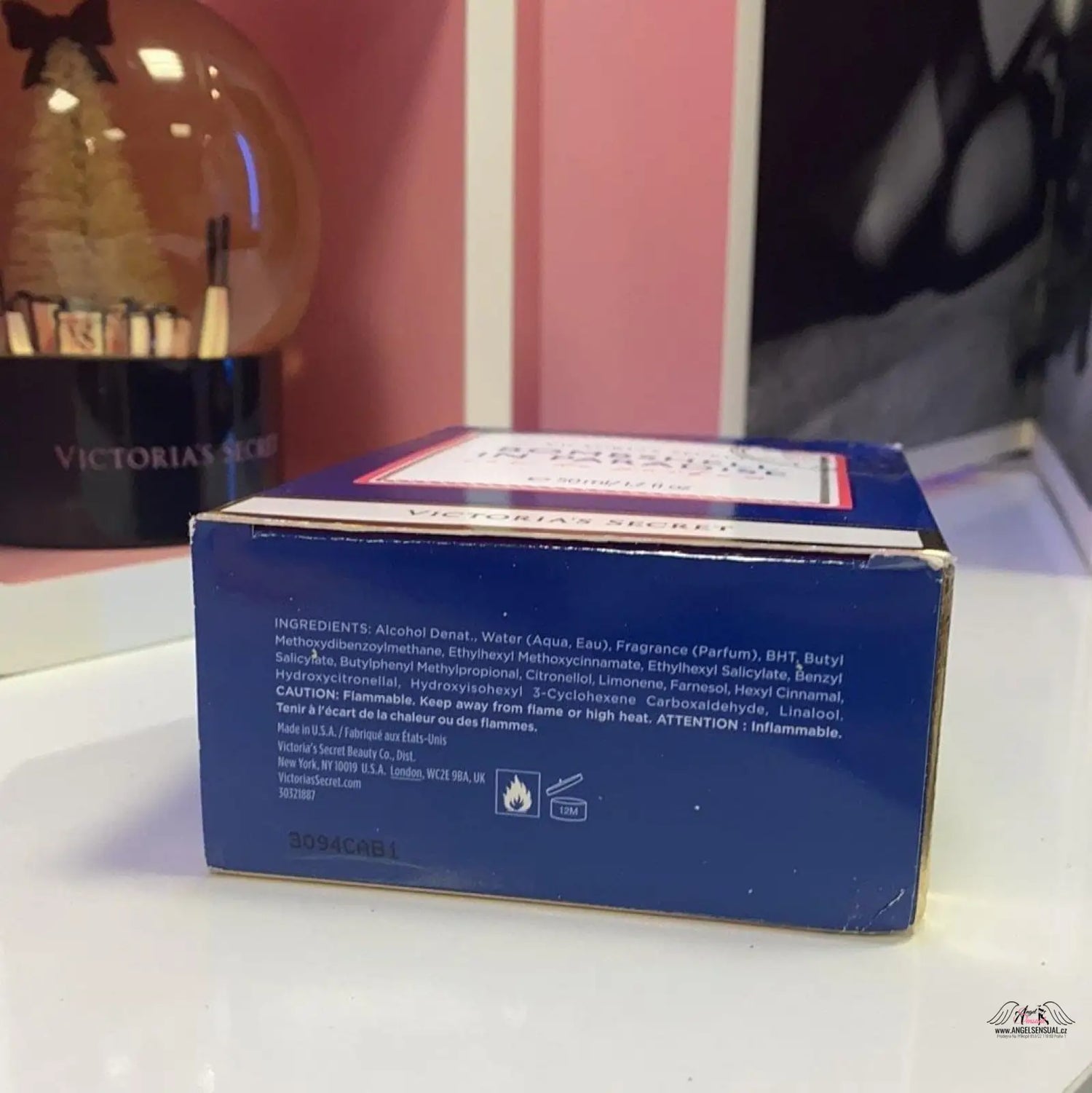 Krabička krému na stole s zrcadlem a parfémem Bombshell in Paradise od Victoria’s Secret