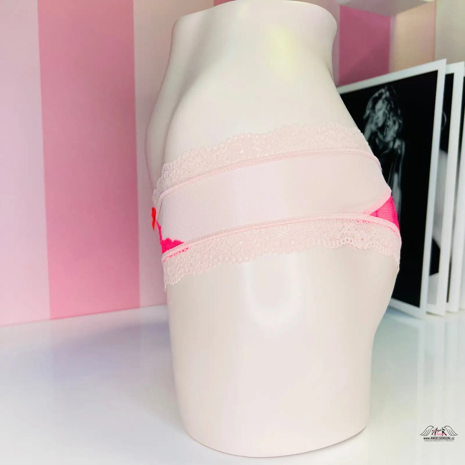 Křivolaká bílá keramická váza s růžovým akcentem u vrchu vedle kalhotek Smyslné Elegance