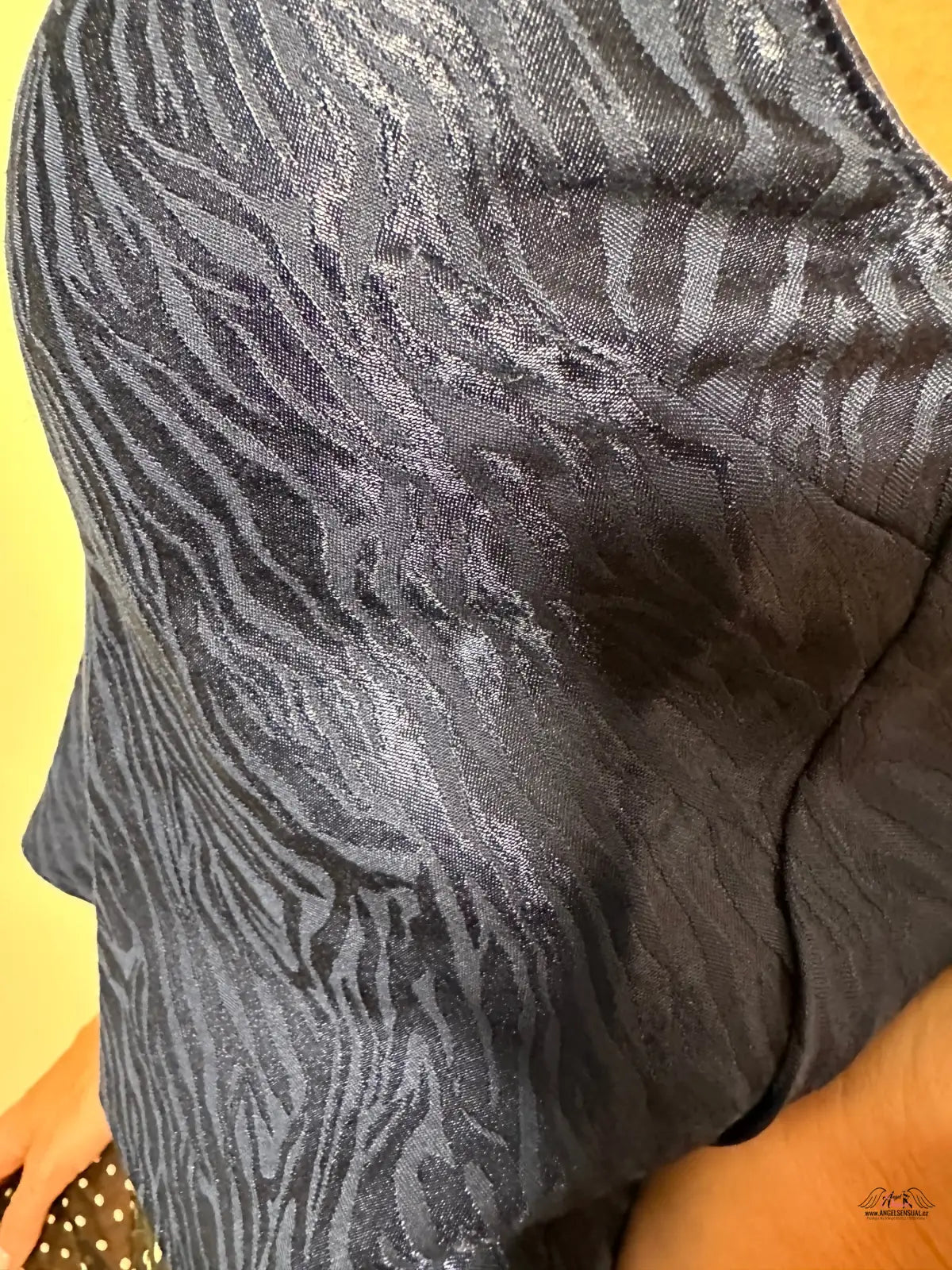 Žena drží černou a stříbrnou kabelku k elegantnímu outfitu